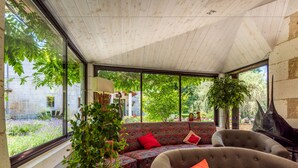 A cozy room with a large window, a sofa, a chair, and a piano. - Moulin de Vigonac (Brantôme en Périgord)