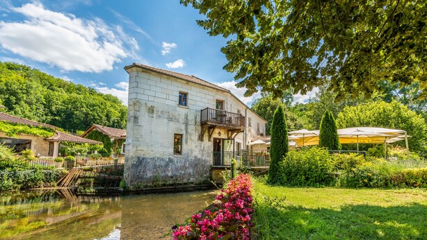 A historic building with a balcony, surrounded by lush greenery and a calm water body. - Moulin de Vigonac (Brantôme en Périgord)