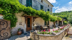 A stone building with a reception area, outdoor seating, and a garden with flowers. - Moulin de Vigonac (Brantôme en Périgord)