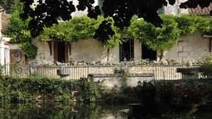 A building with a stone facade, a wrought iron fence, and a small pond with ducks. - Moulin de Vigonac (Brantôme en Périgord)