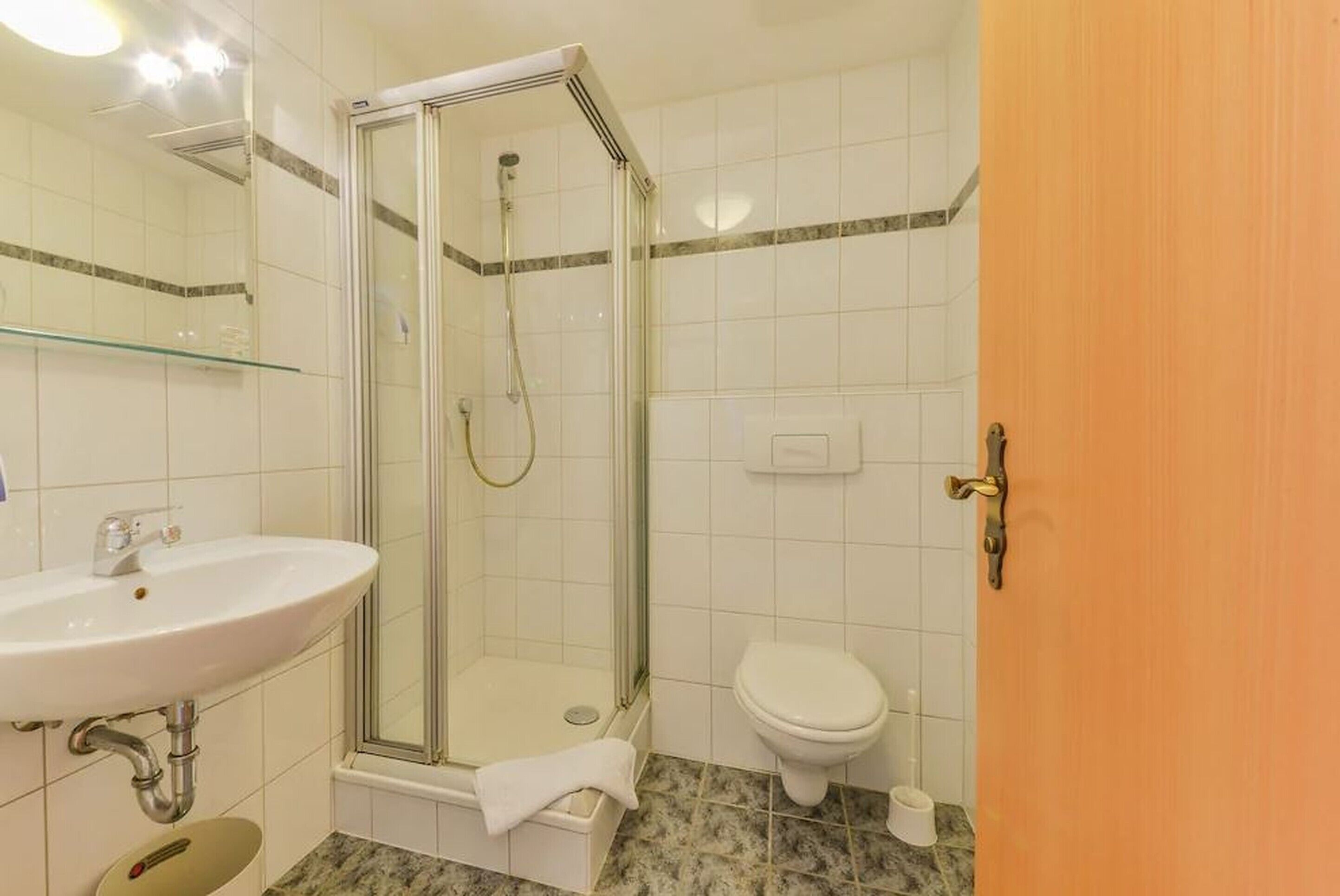 Un baño con ducha de vidrio, un lavamanos blanco y un inodoro.