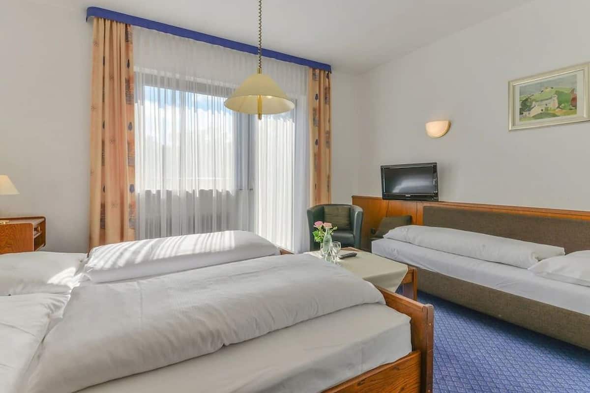 Habitación de hotel con dos camas, un escritorio, una silla, un televisor y un cuadro en la pared.
