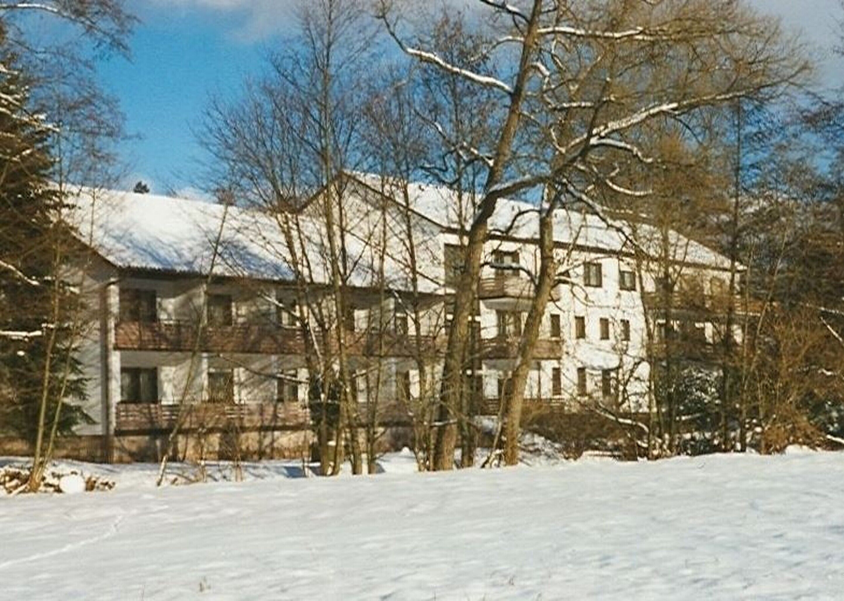 A multi-story building with a symmetrical facade, surrounded by snow-covered ground and leafless trees.