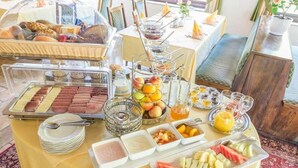 Una mesa de buffet con diversos alimentos para el desayuno, como pasteles, frutas y bebidas.