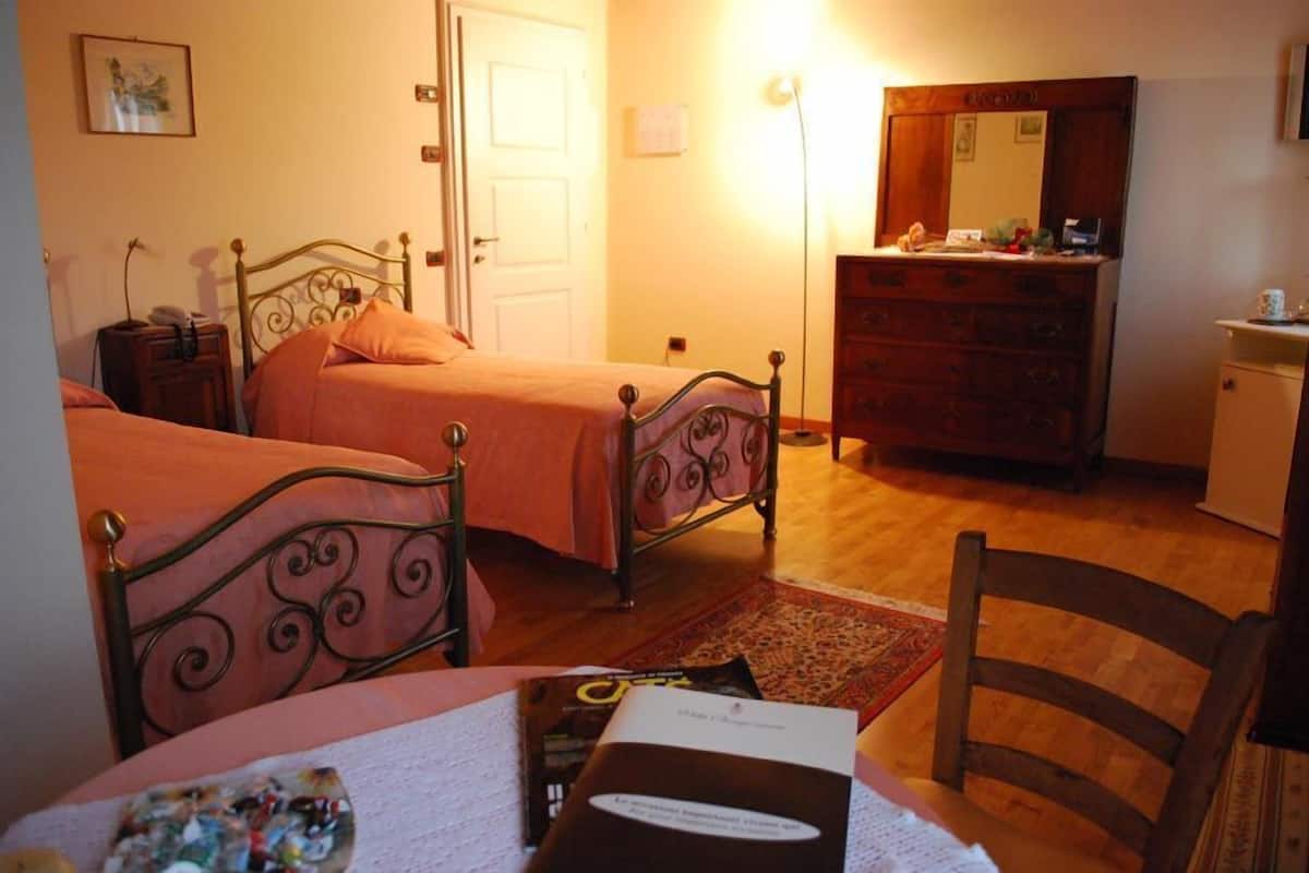 A bedroom with two beds, a dresser, a mirror, and a bedside table.