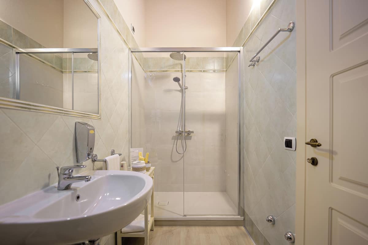 A modern bathroom with a glass-enclosed shower, a sink, and a mirror.
