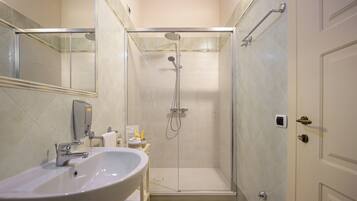 A modern bathroom with a glass-enclosed shower, a sink, and a mirror.