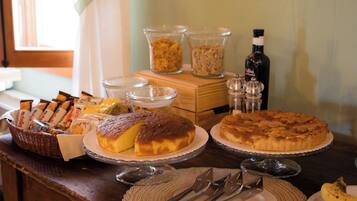 A breakfast buffet with various food items, including pastries and bread, on a wooden table.