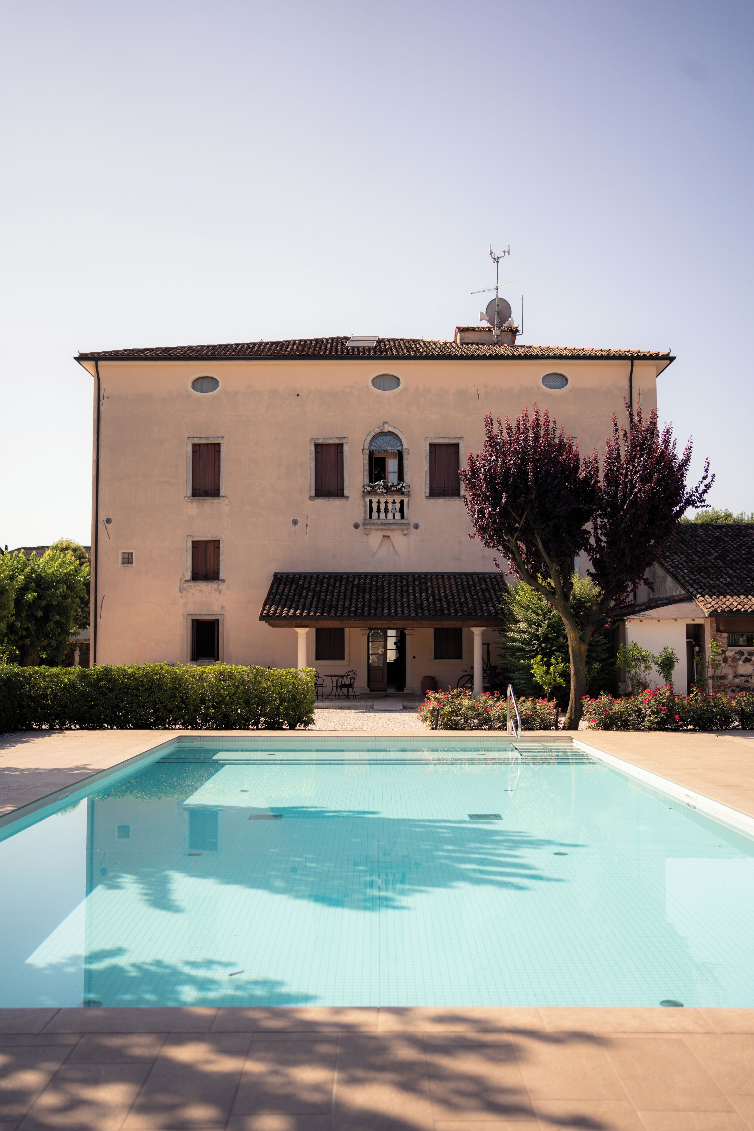 A building with a swimming pool, a tiled roof, and a balcony.