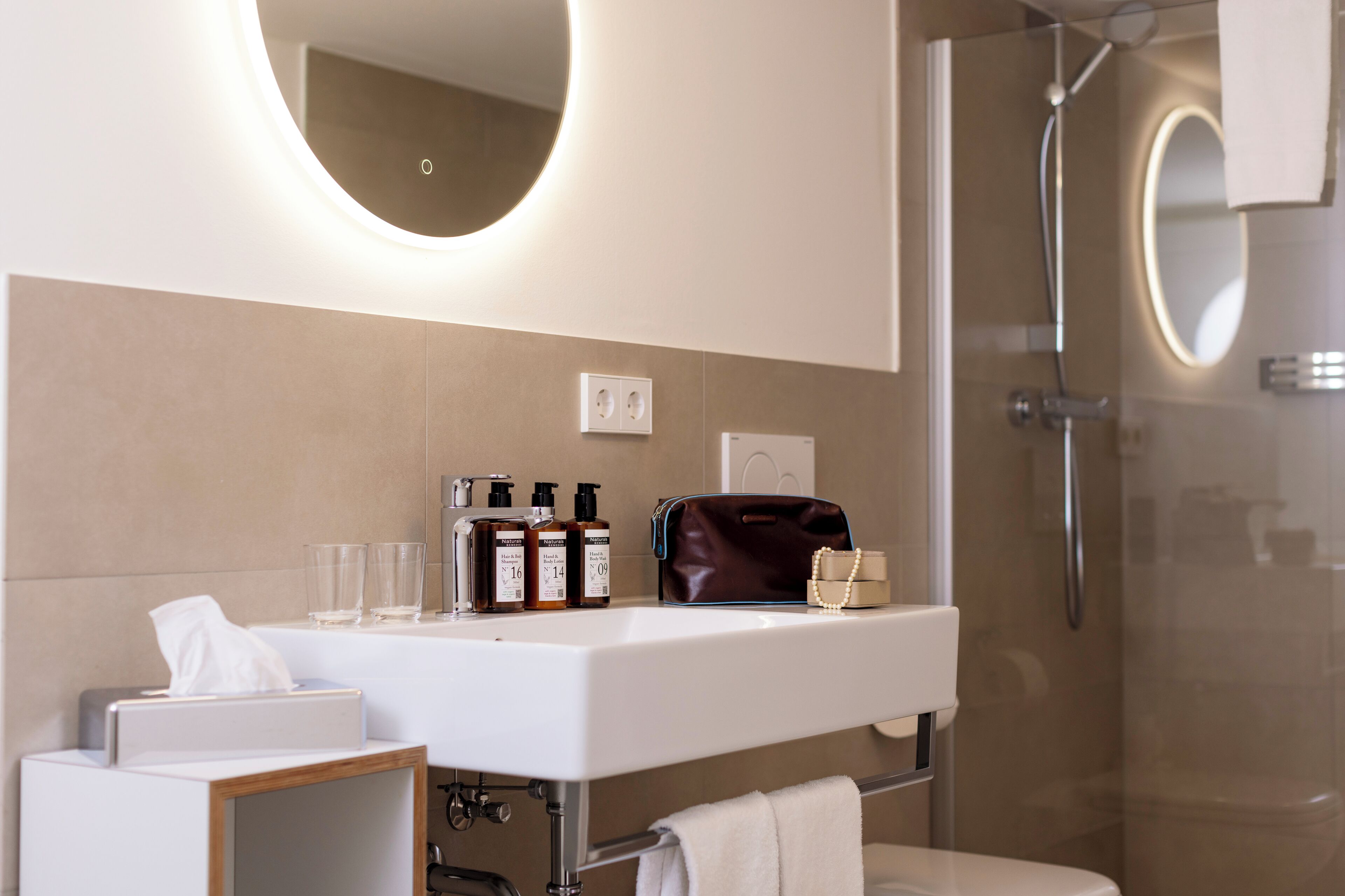 A modern bathroom with a white sink, a mirror, and a glass shower enclosure.
