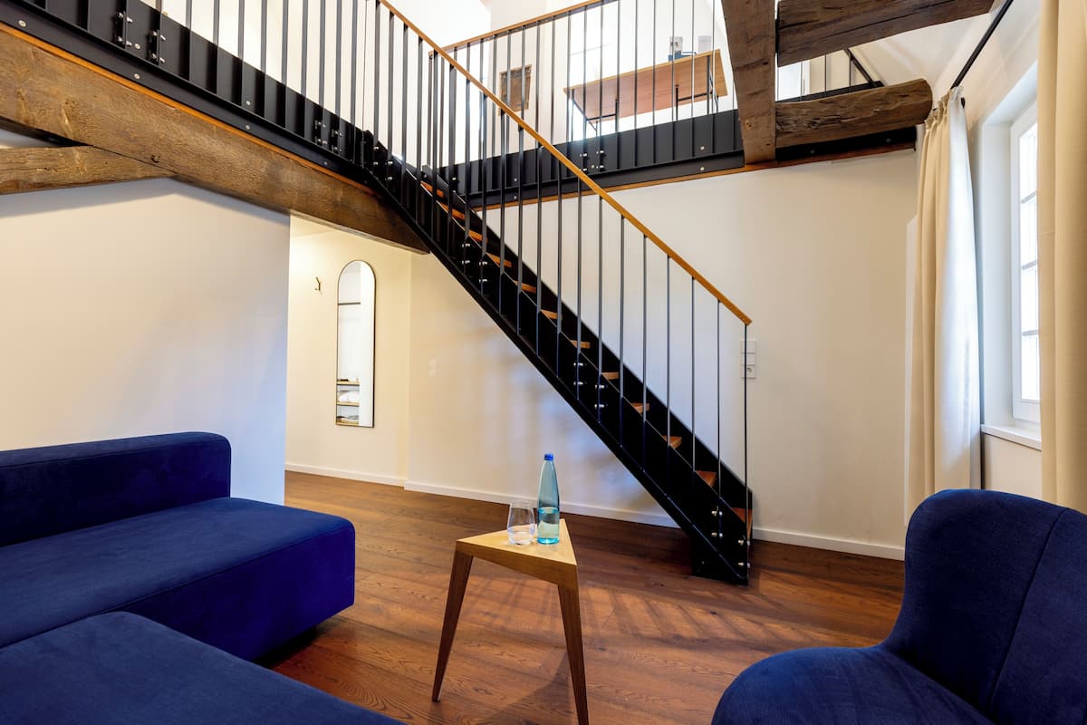 Un salon moderne avec un escalier en bois, des canapés bleus et une petite table en bois.