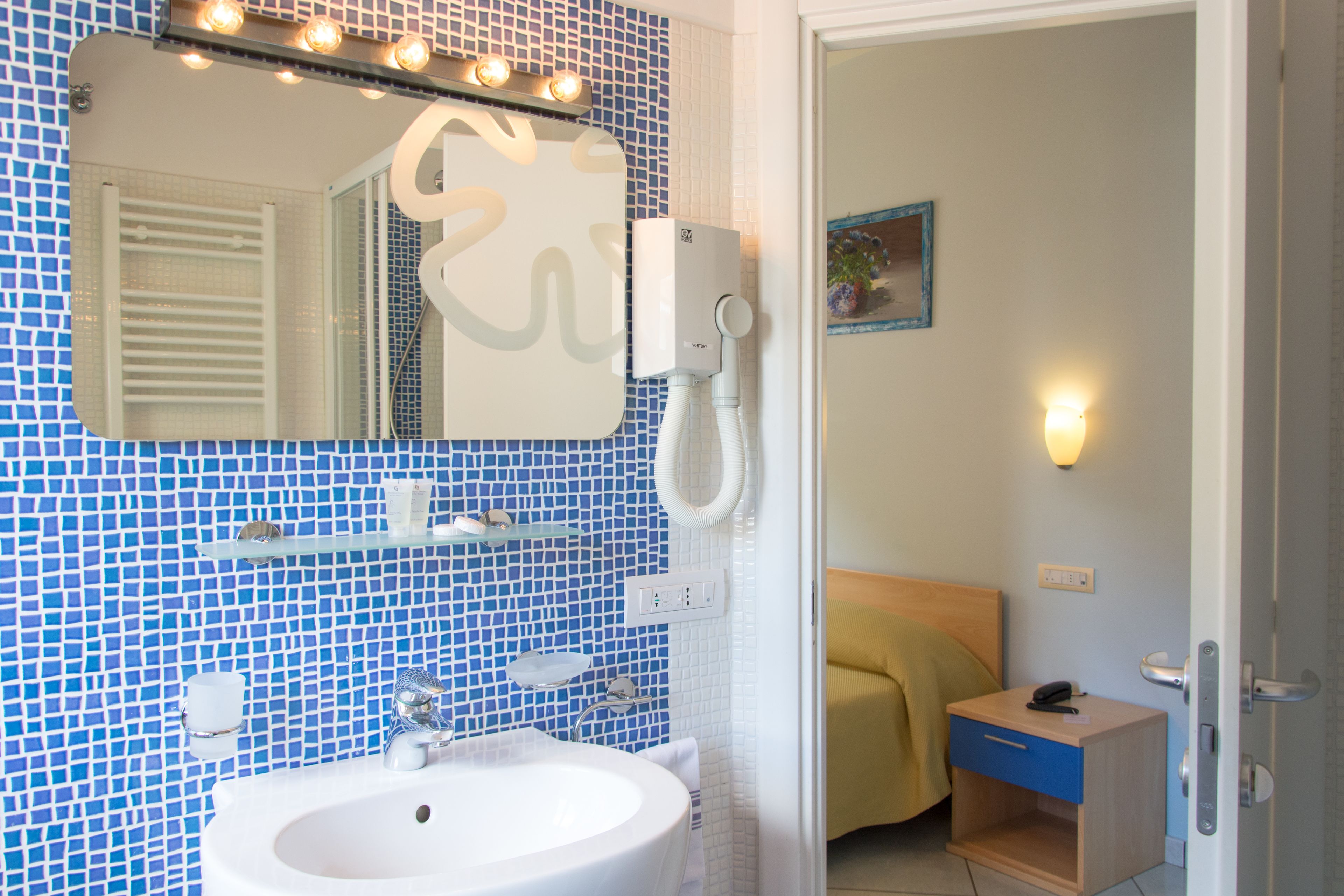 A bathroom with a sink, mirror, and a shower area.
