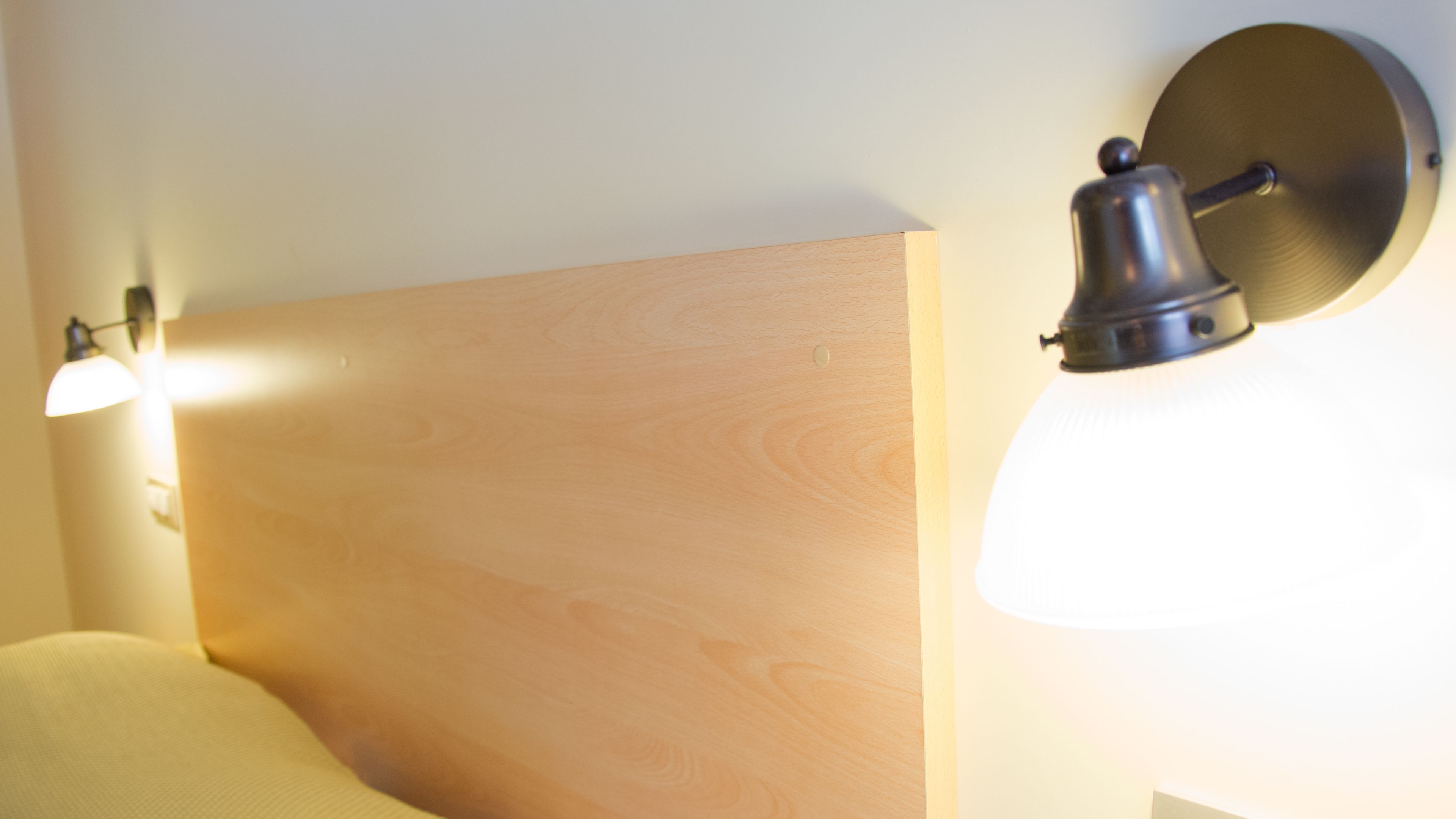 Ein hölzerner Kopfseitenrahmen mit einer an der Wand befestigten Leuchte rechts.