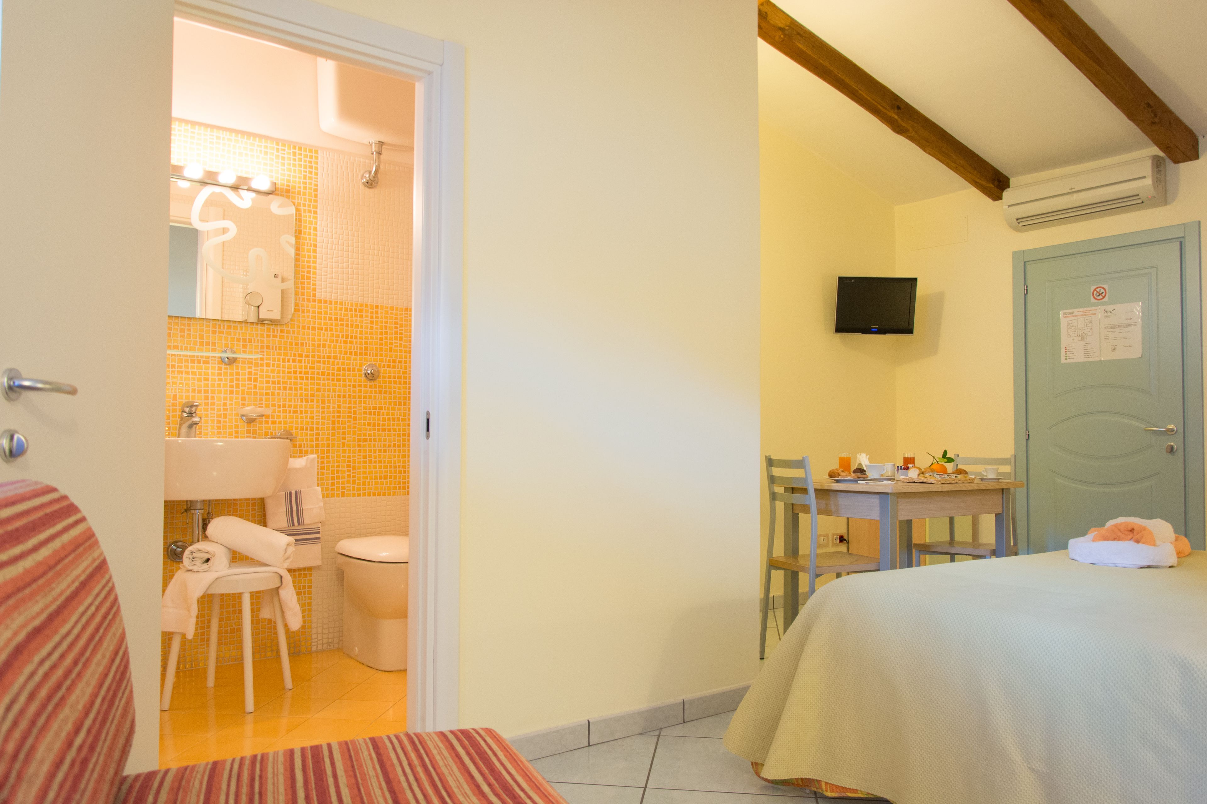 Une chambre d’hôtel avec une salle de bain, un coin repas et un lit.