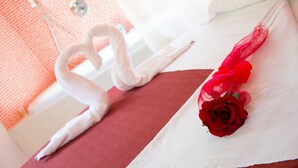 Una cama con una rosa roja y una toalla con forma de corazón.