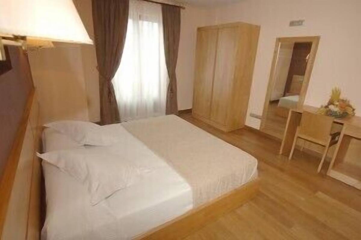 Une chambre à coucher avec un lit, un bureau, une armoire et un miroir.
