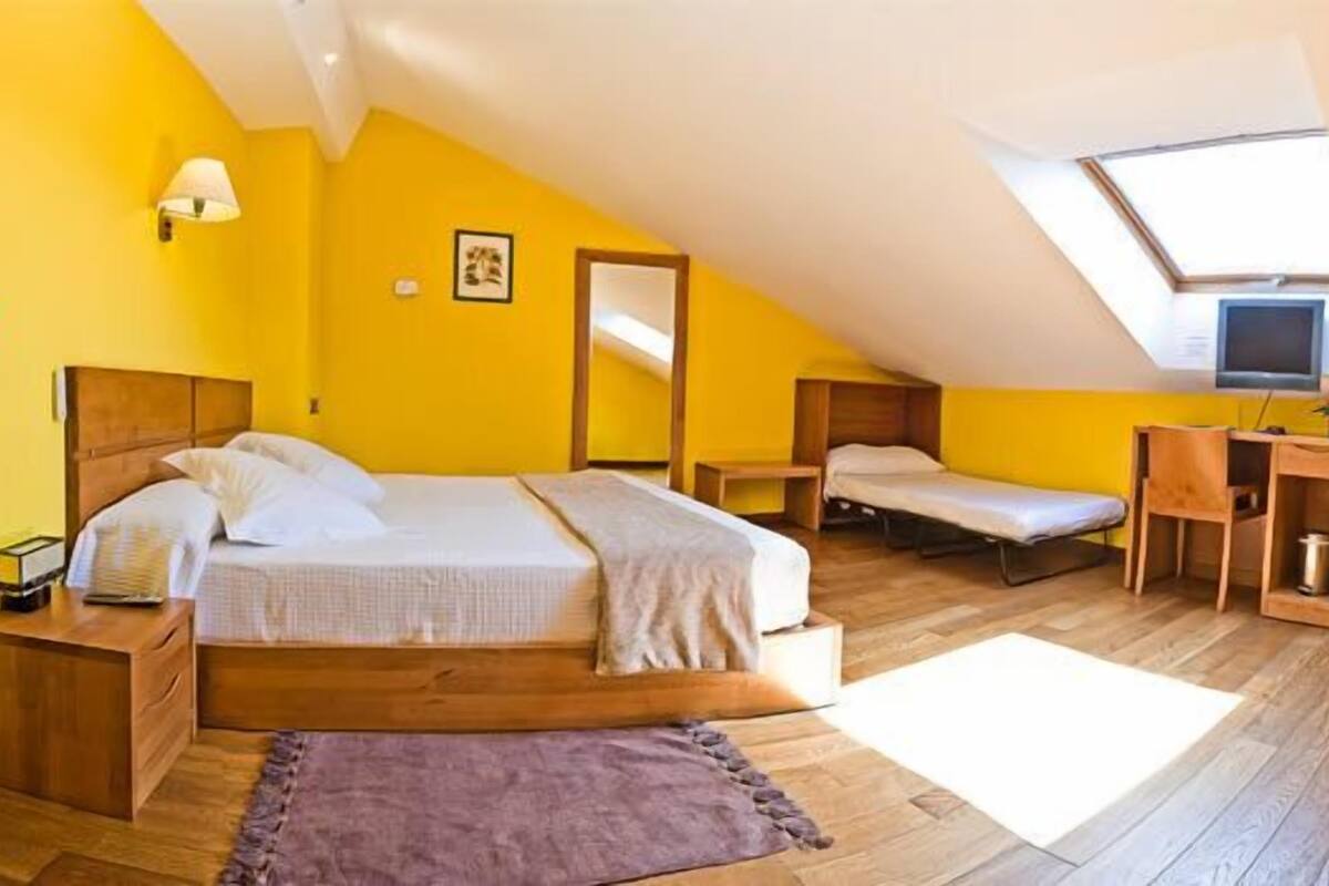 Une chambre à coucher comprenant un lit, des tables de chevet, un bureau, une chaise, un téléviseur et une fenêtre.
