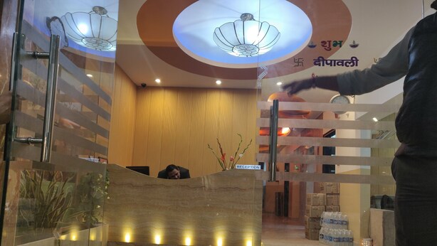 A reception area with a marble reception desk, a wooden wall, and a ceiling with a floral light fixture.