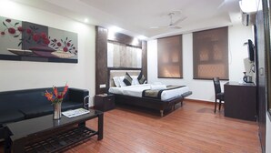 A modern hotel room with a bed, a sofa, a coffee table, and a desk.