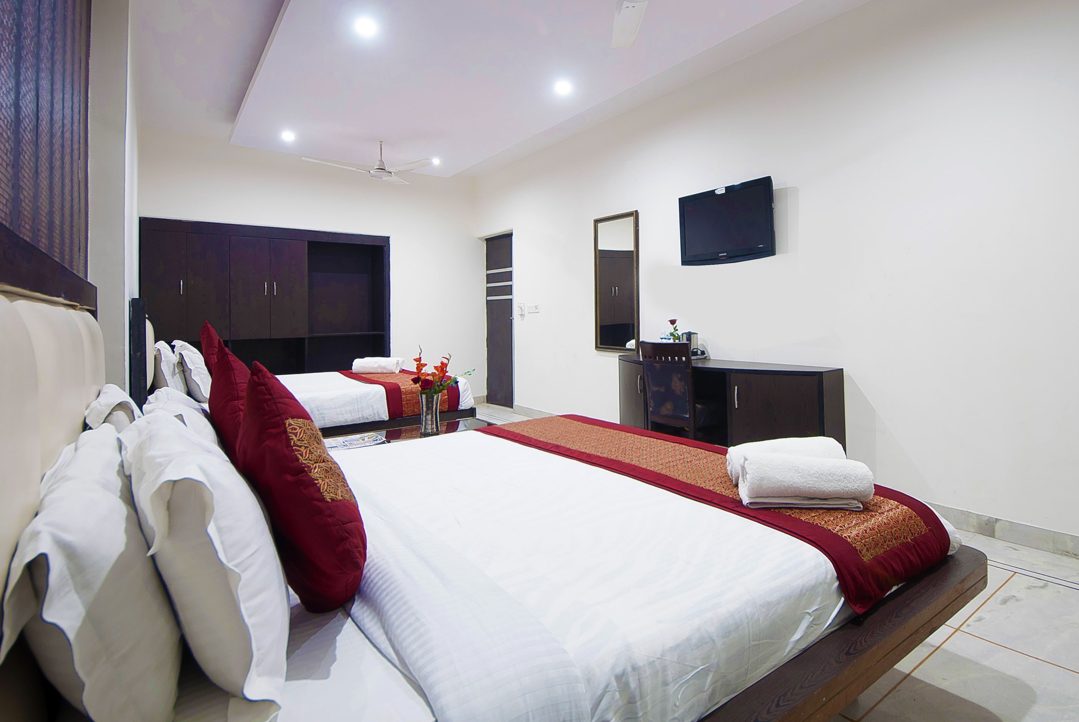 A hotel room with two beds, a flat-screen TV, a mirror, and a wardrobe.