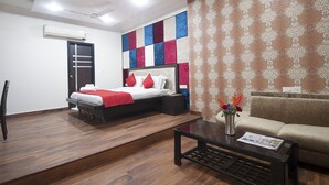 A hotel room with a bed, a sofa, a coffee table, and a patterned wall.