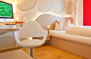 Un dormitorio moderno con una cama, una computadora y un escritorio.