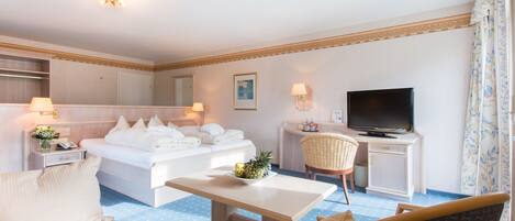 A hotel room with a bed, a desk, a television, a chair, and a small table with a fruit bowl.