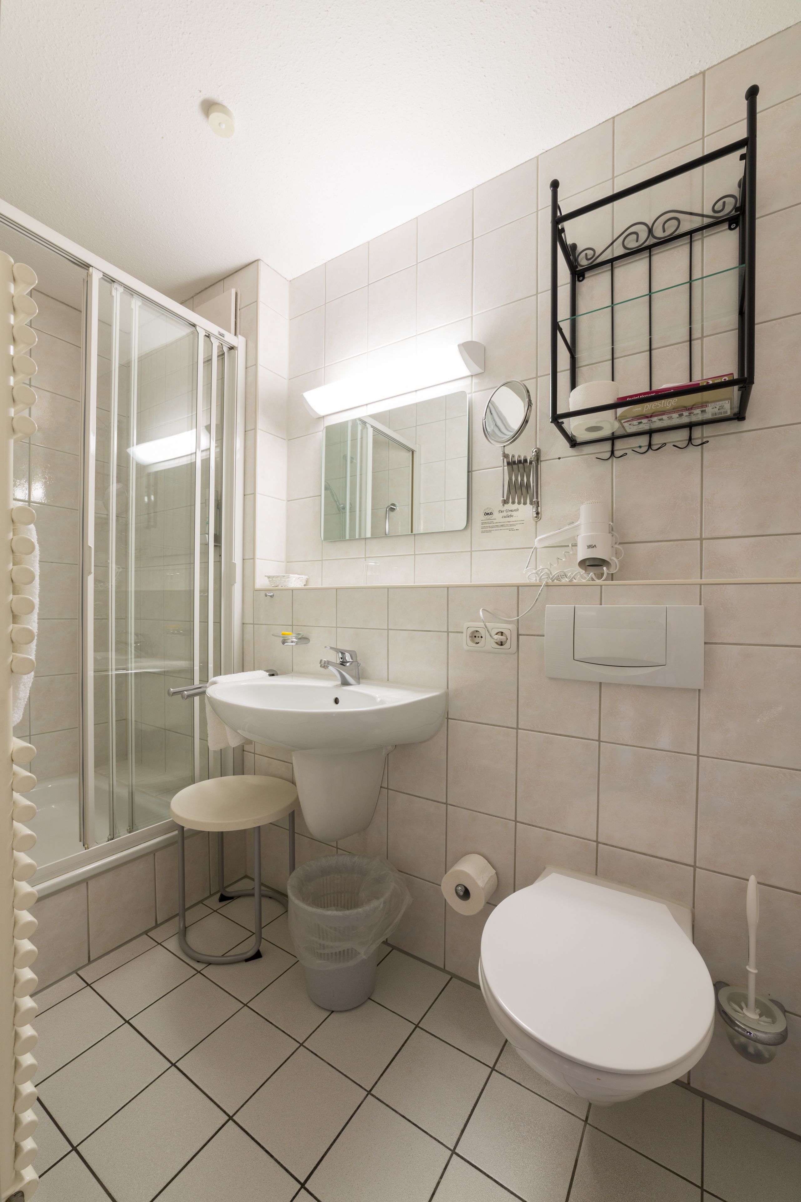 A bathroom with a shower, sink, toilet, and a mirror.