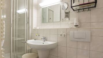 Ein Badezimmer mit Dusche, Waschbecken, Toilette und Spiegel.