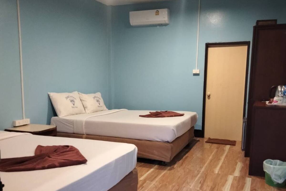 Una habitación con dos camas, piso de madera, una puerta y un equipo de aire acondicionado.