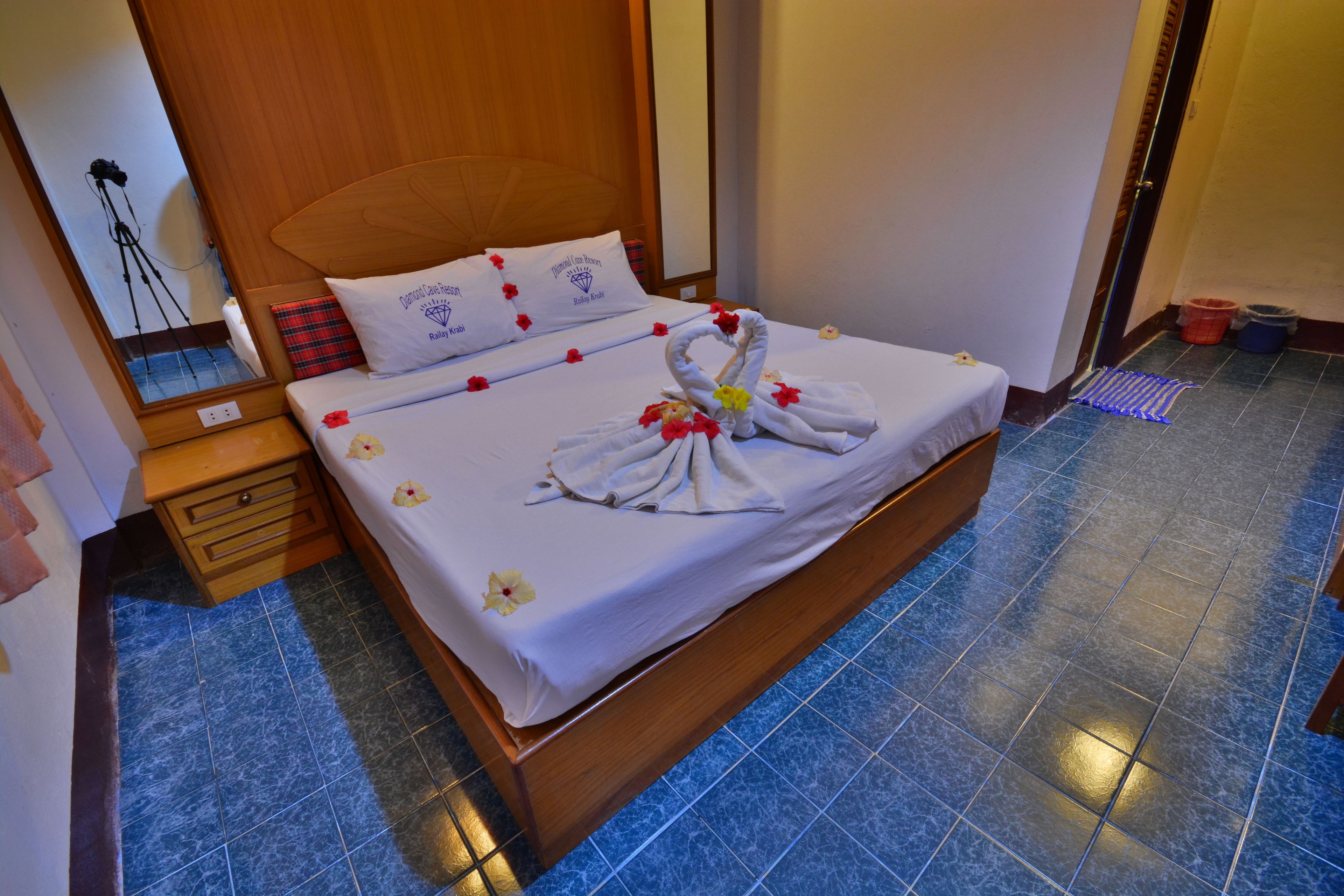 A neatly made bed with a white bedspread, pillows, and a towel arrangement.