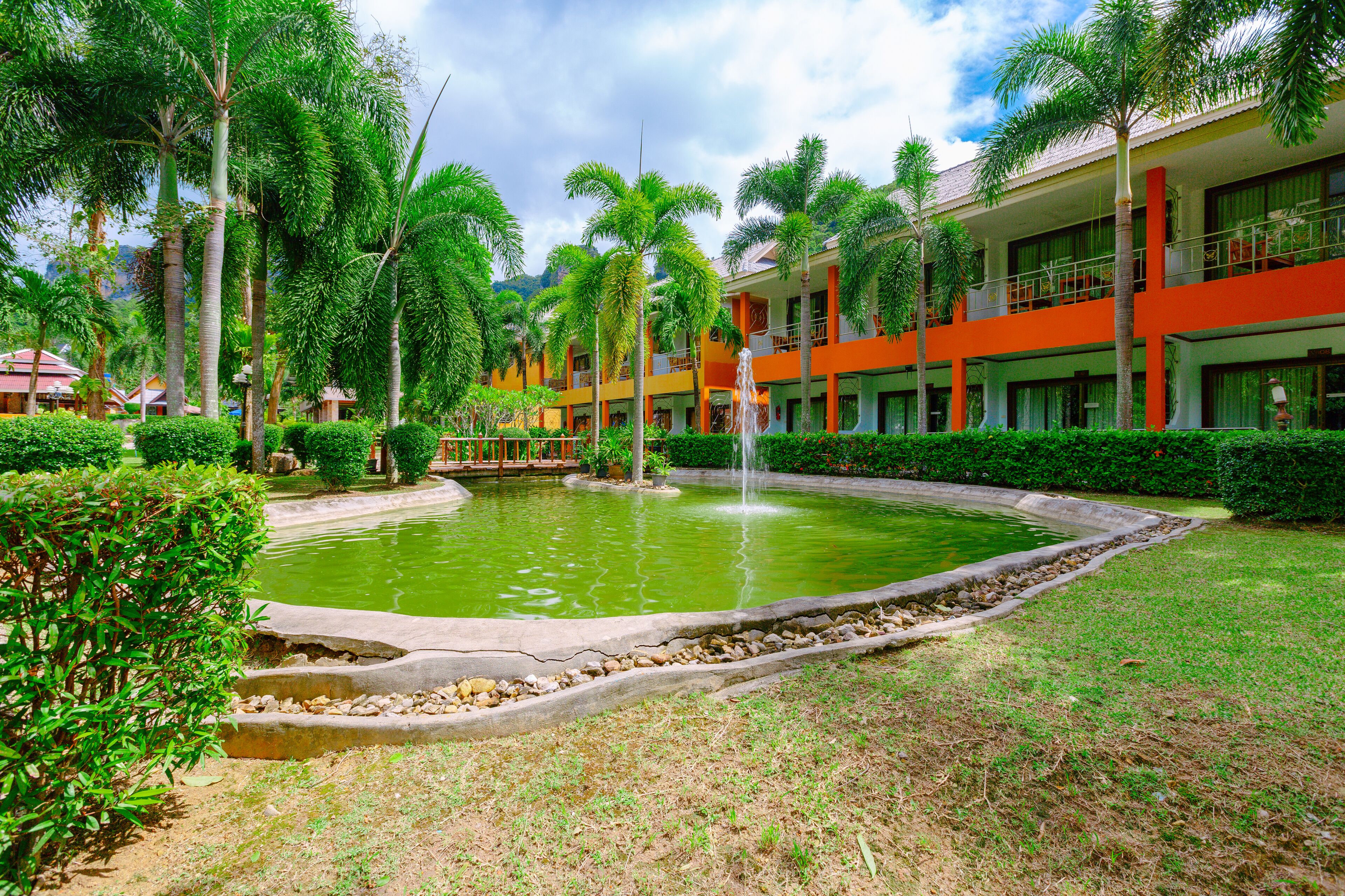 A hotel with a swimming pool surrounded by palm trees and a fountain.