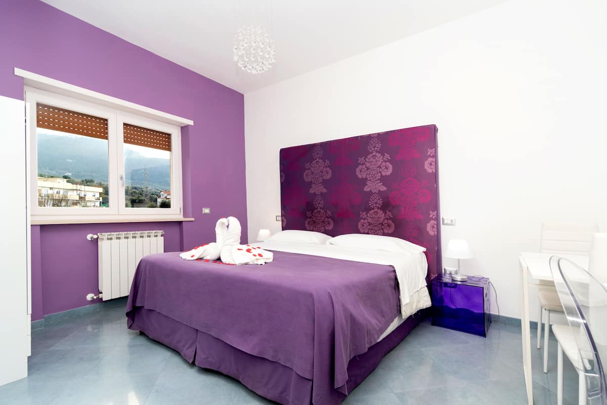 A room with a bed, a window, a radiator, a desk, and a chair.