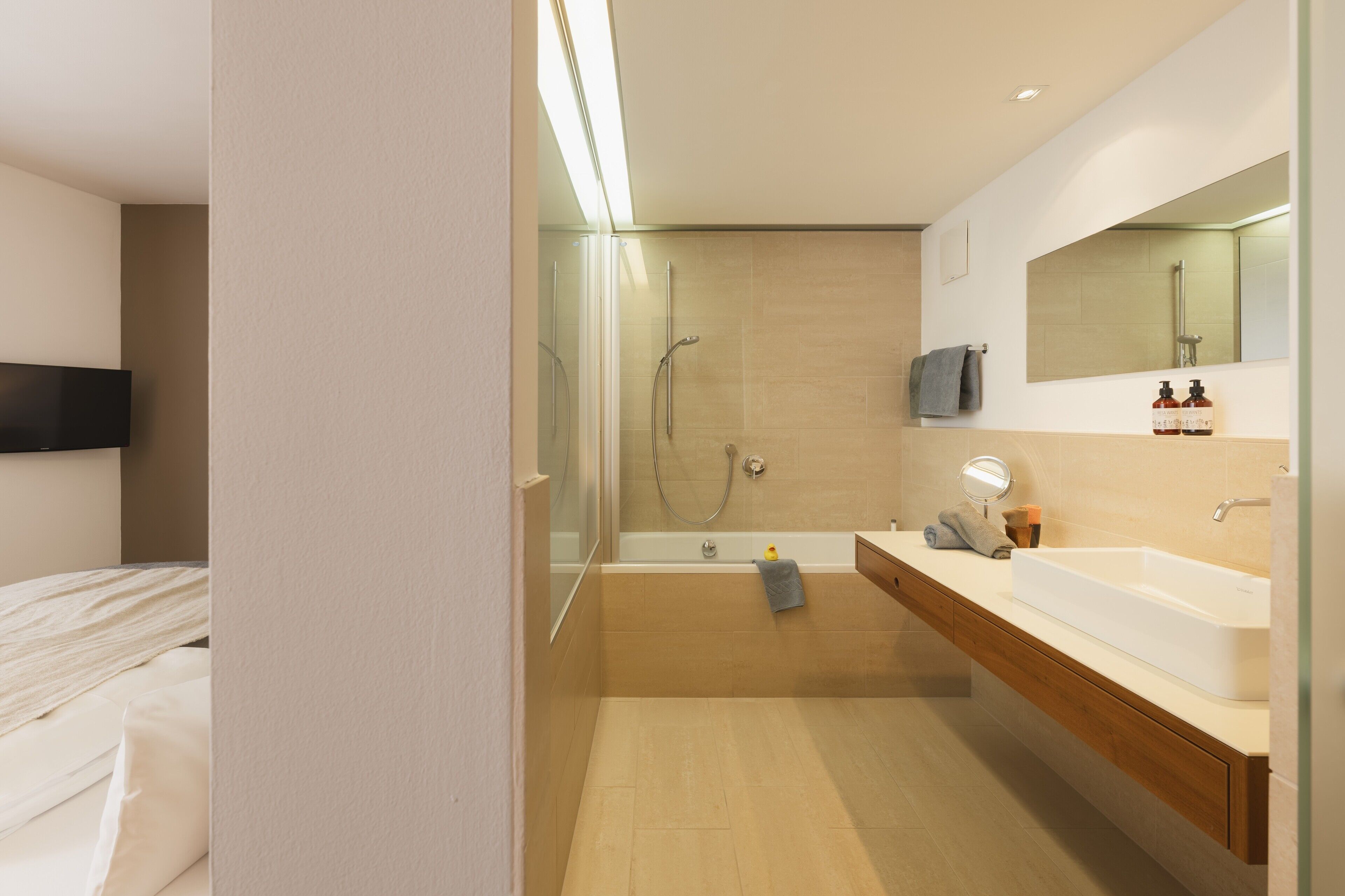 A modern bathroom with a glass-enclosed shower, a large sink, and a mirror above the vanity.