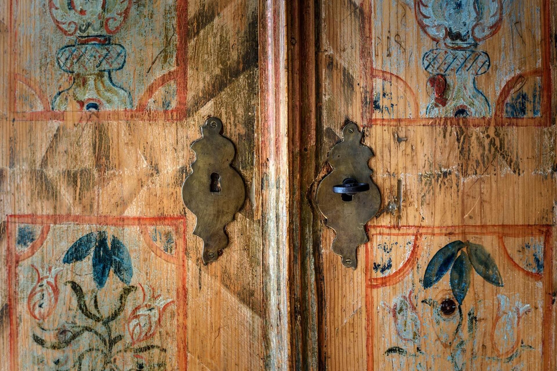 Uma porta de madeira com entalhes elaborados e duas maçanetas de metal.