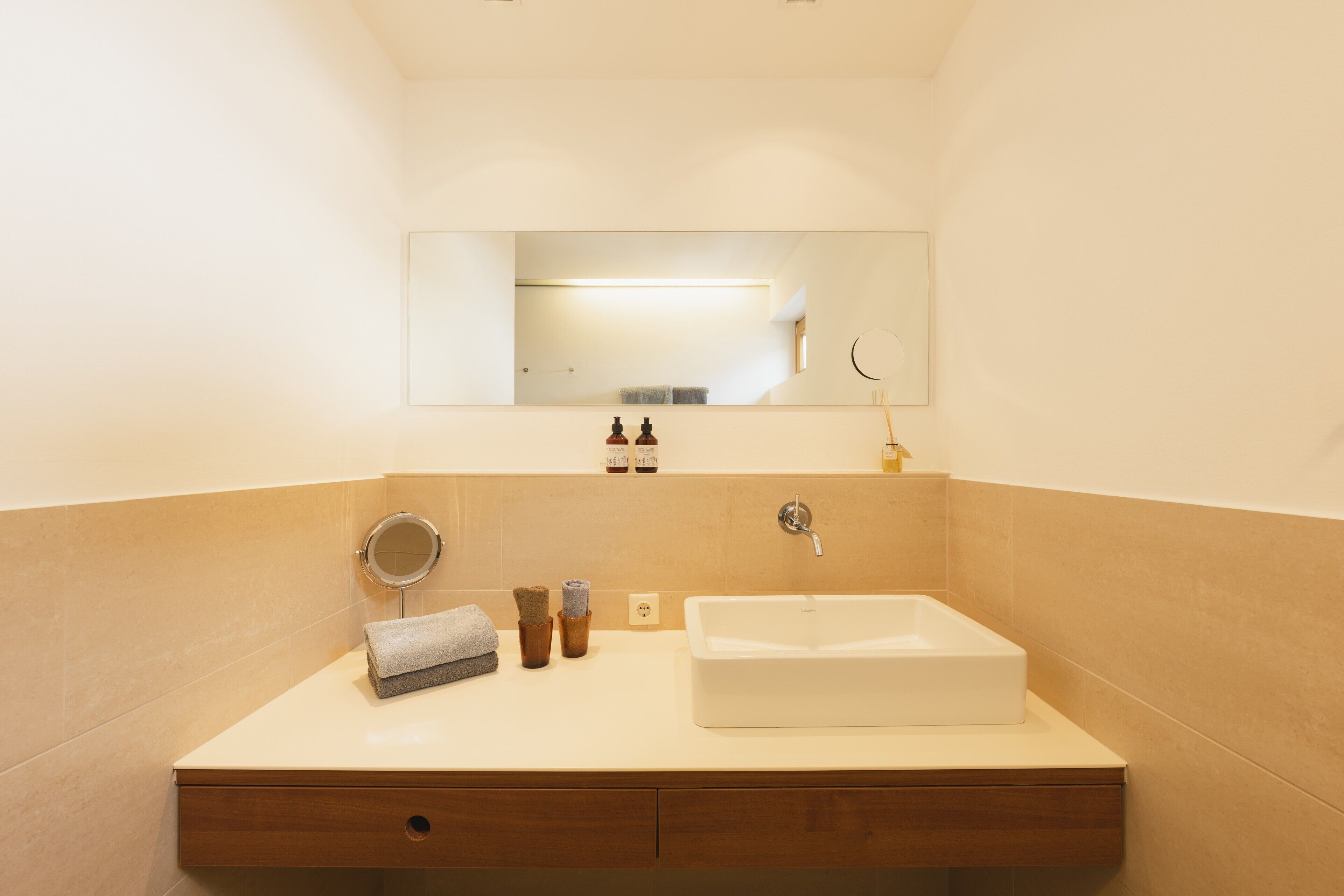 Un baño moderno con un lavamanos grande, un espejo y un perchero para toallas.