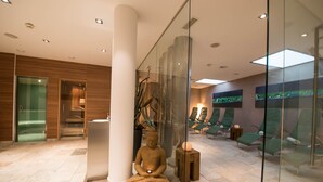 A modern spa area with a meditation statue, a reception desk, and a seating area with green chairs. - Skihotel Galzig (Sankt Anton am Arlberg)
