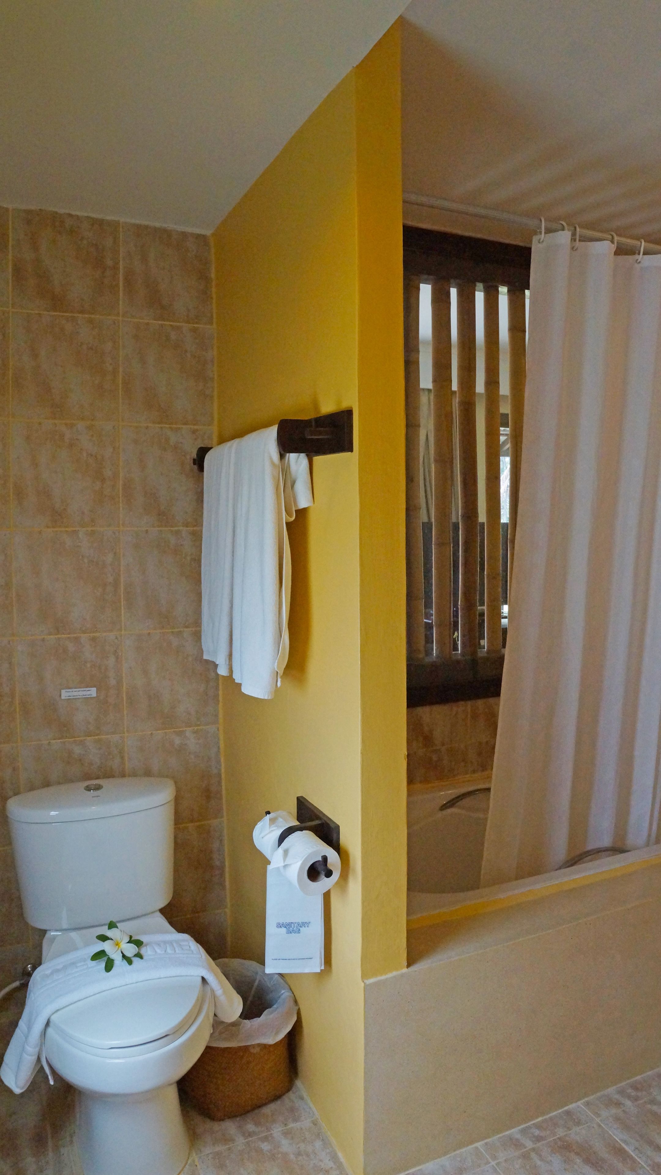 A bathroom with a toilet, a sink, a shower curtain, and a towel rack.