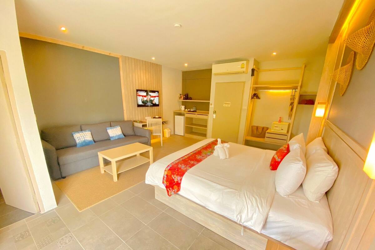 Een hotelkamer met een bed, een bank, een televisie, een bureau en een kledingkast.