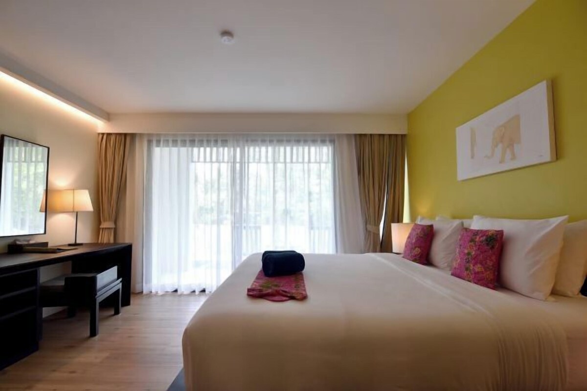 A hotel room with a large bed, a desk, and a chair.