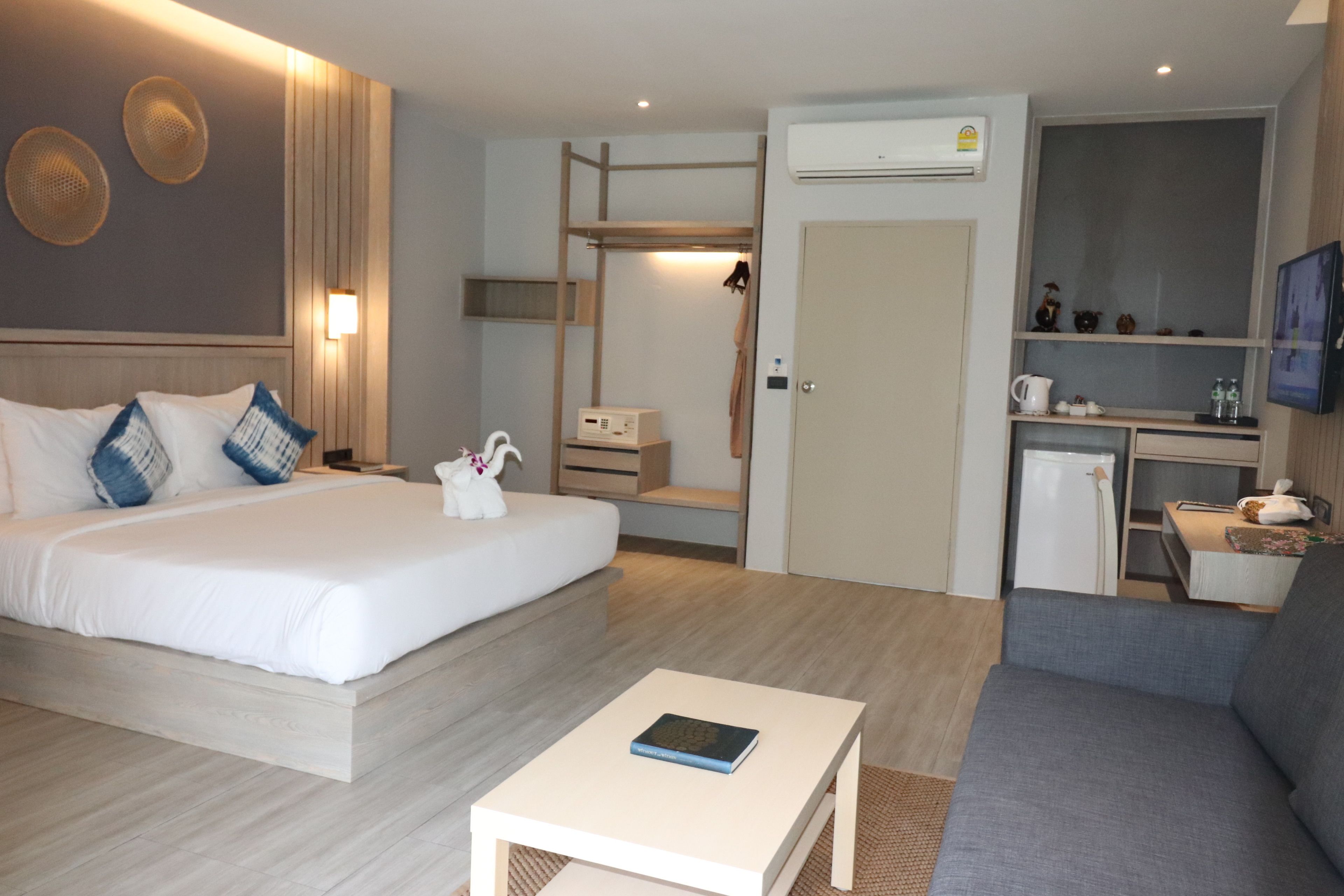 A hotel room with a bed, a desk, a sofa, and a small kitchenette.