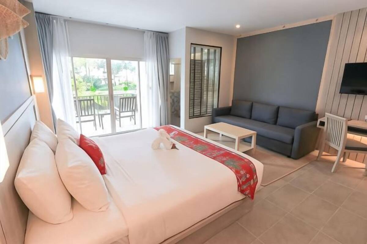 Een hotelkamer met een bed, een bank, een televisie en een balkon.