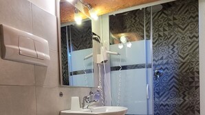 Casa de banho com sanita, lavatório e chuveiro.