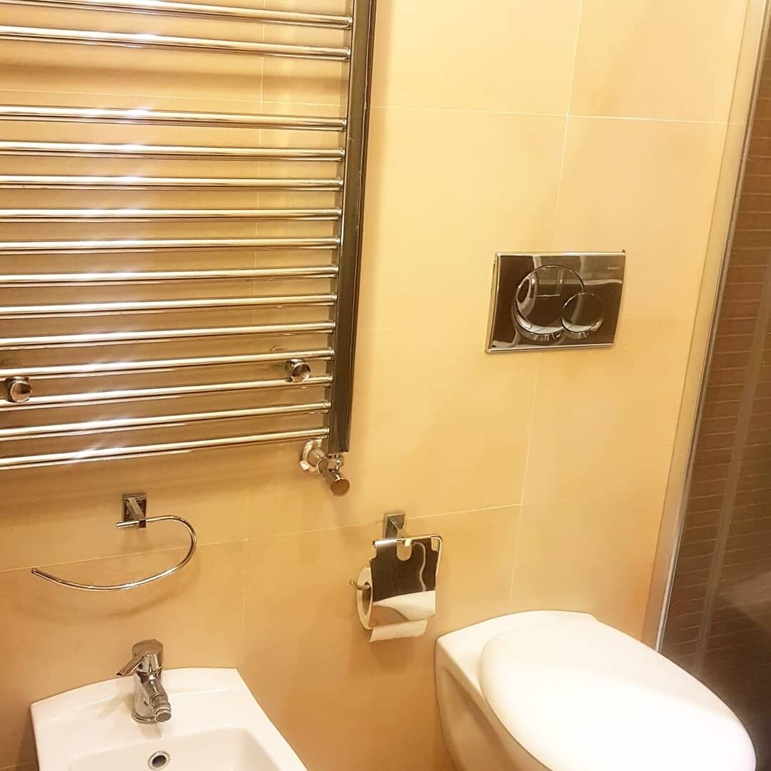 Une salle de bain avec un lavabo blanc, des toilettes, un porte-serviettes et un miroir.