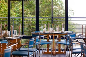 Enjoy meals with a view of lush greenery from this dining area, featuring comfortable seating and elegant table settings.