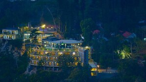 Un hotel de varios pisos con un patio central, rodeado de abundante vegetación.