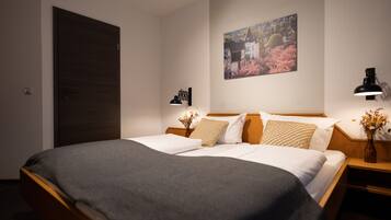 A neatly made bed with a dark blanket, a wooden headboard, and two bedside tables with lamps.