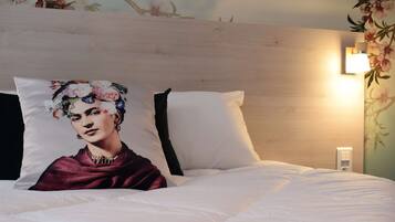 A bed with white bedding, a floral pillow, and a nightstand with a lamp.
