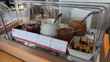 A buffet area with various food items and condiments.