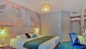 A hotel room with a large bed, a blue chair, a wooden wardrobe, and a wall mural. - Brit Hotel Au Pays de Vitre (Etrelles)